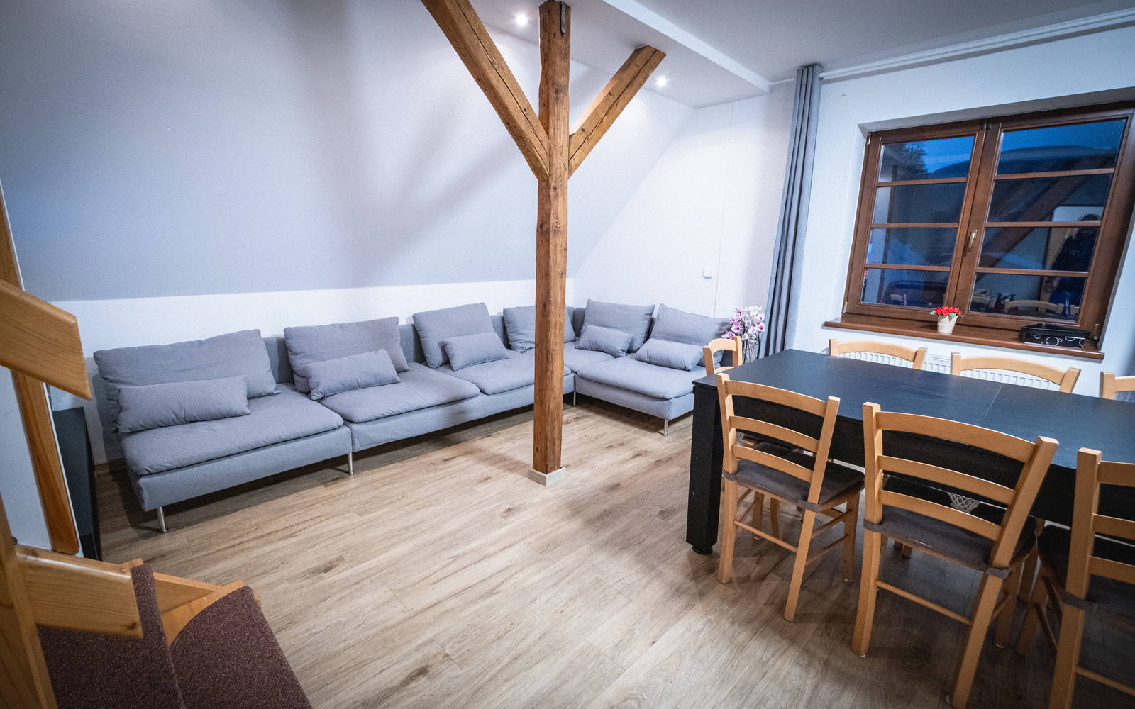 Obývací část apartmá Suite — dlouhá sedací souprava pod trámy